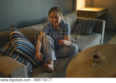 Young Happy Woman Using Nail File While Giving Herself Pedicure At Home. Female Applying Nail Polish