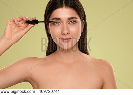 Young Female With Bare Shoulders Looking At Camera And Applying Mascara On Eyelashes During Beauty R