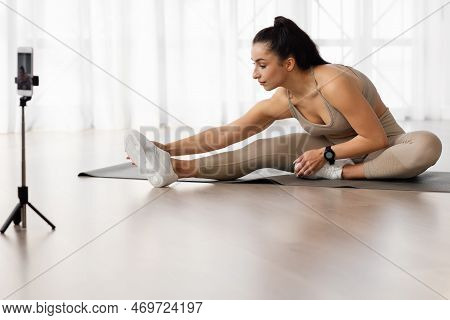 Young Woman Yoga Instructor Broadcasting While Strecthing At Home