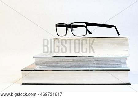 Three Thick Book On A Table With Glasses As A Visual Aid And A White Background