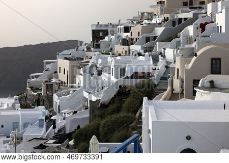 Imerovigli, Santorini, Greece - July 1, 2021: Whitewashed Houses With Terraces And Pools And A Beaut