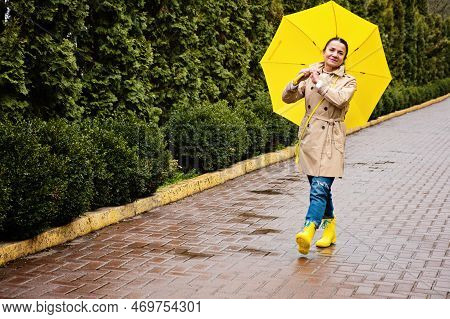 Happy Senior Woman In Yellow Rain Coat With Yellow Umbrella Encouraging Self-care And Relaxation, Us