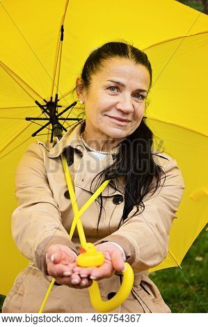 Happy Senior Woman In Yellow Rain Coat With Yellow Umbrella Encouraging Self-care And Relaxation, Us