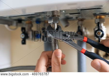Man Repairing Gas Boiler With Waterpump Plier, Closeup
