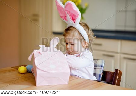 Cute Little Toddler Girl Wearing Easter Bunny Ears Playing With Colored Pastel Eggs. Happy Baby Chil