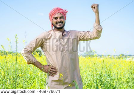 Happy Famer Showing Stroing Gesture While Standing At Farmland By Looking At Camera - Conept Of Conf