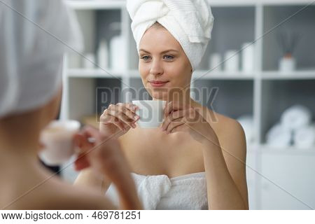 Young Woman Sits In The Bathroom In Front Of The Makeup Mirror And Does Cosmetic Procedures. Beautif