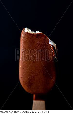 Ice Cream On A Stick On A Black Background. Ice Cream Bite. Bitten Ice Cream. Pieces Of Ice Cream.\n
