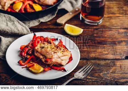 Oven Baked Chicken Thighs With Red Bell Peppers And Lemon On White Plate.