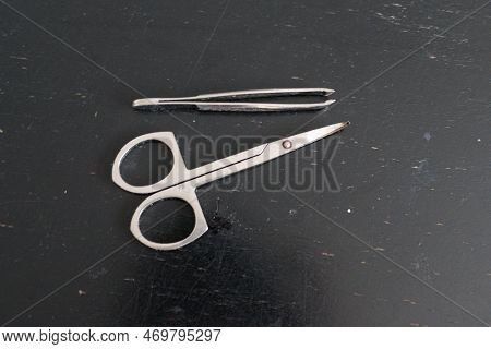 Scisors And Tweesers On A Black Table