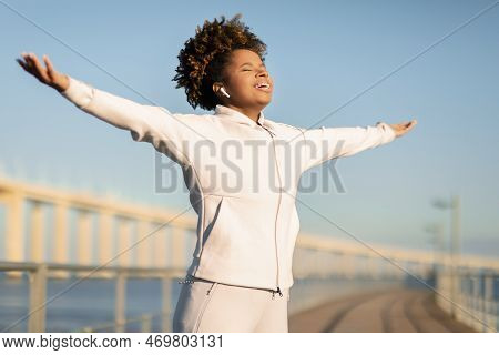 Young Black Female Jogger Spreading Arms And Breathing Fresh Air Outdoors