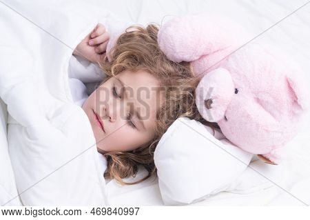 Little Boy Sleeps. Lovely Face Of Blonde Caucasian Child, Sleeping With A Toy Teddy Bear On Bed. Swe