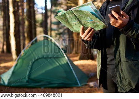 Adult Hiker With Backpack Using Mobile Phone And Map In Forest Near His Tent. Hiking Elderly Man In 