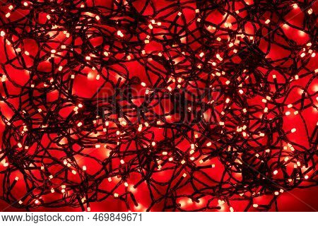 Tangled Black Wire Garlands With Red Light Bulbs On A Red Background