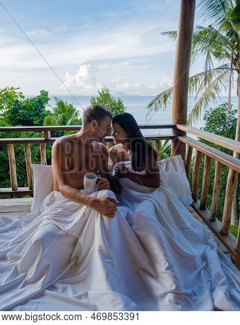 Couple Waking Up In Bed Looking Out Over Ocean During Sunrise At Wooden Hut Moutains Of Thailand