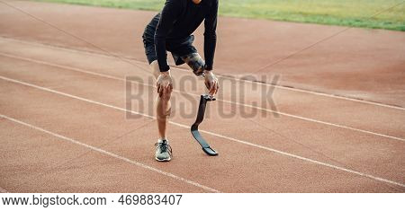 Tired Runner With Prosthetic Leg Standing On Running Track And Taking A Break.