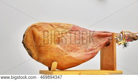 A Front Leg Of Serrano Ham Mapped On A Wooden Stand On A White Background.