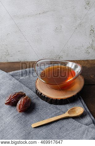 Natural Organic Healthy Date Syrup In A Glass Bowl With Whole Dates And Wood Spoon On The Background