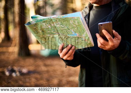 Adult Hiker With Backpack Using Mobile Phone And Map In Forest Near His Tent. Hiking Elderly Man In 