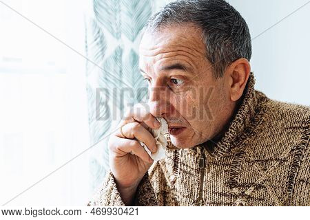 Middle-aged Man In Warm Sweater, Blows Nose Into Disposable Paper Napkin, Sneezes And Coughs, Is Sic
