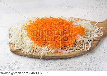 Wooden Board With Chopped Cabbage And Grated Carrots On A Light Blue Background. Preparation Of Cole