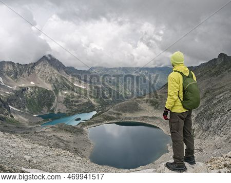 Man With Backpack Looking At Imeretinsky Lake Of Silence And Lake Celestial At Mountains Background 