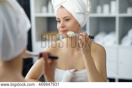Young Woman Sits In The Bathroom In Front Of The Makeup Mirror And Does Cosmetic Procedures. Beautif