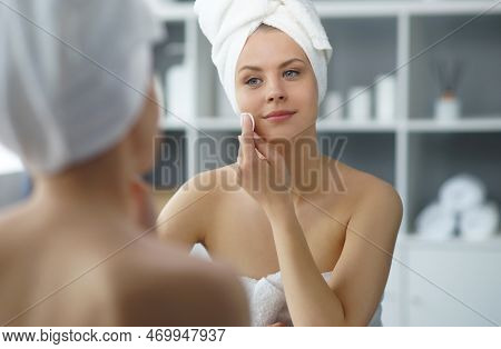 Young Woman Sits In The Bathroom In Front Of The Makeup Mirror And Does Cosmetic Procedures. Beautif