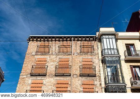 Old Residential Building With Windows Boarded Up To Prevent Squatters From Entering