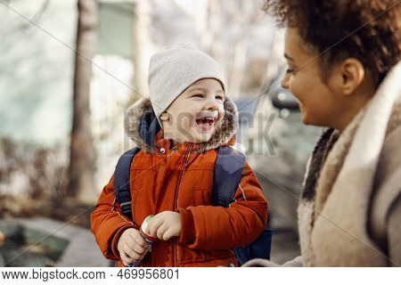 Caregiver Laughing With Kindergarten Child In The Schoolyard. Happy Kindergarten Child Laughing And 