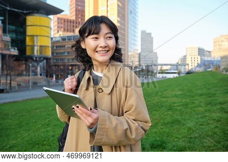 Happy Asian Girl Stands On Street, University Student Walks With Digital Tablet In Hands And Smiles,
