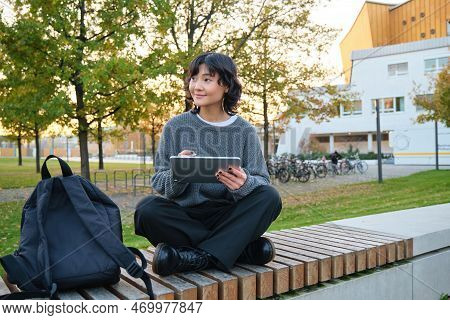 Young Girl, Korean Artist Or Art Student Sits In Park With Digital Tablet, Draws With Graphic Pen, S