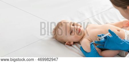 Doctor Vaccinating Smiling Baby In Clinic. One Year Little Baby Get An Injection. Pediatrician And P