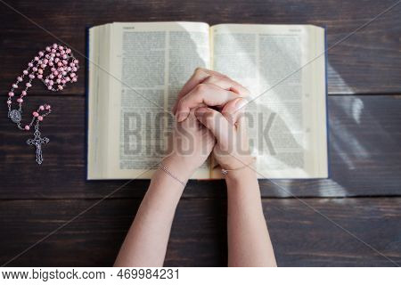 Hands Folded In Prayer On A Holy Bible   And Cross Rosary On The Side .concept For Faith, Spirtualit