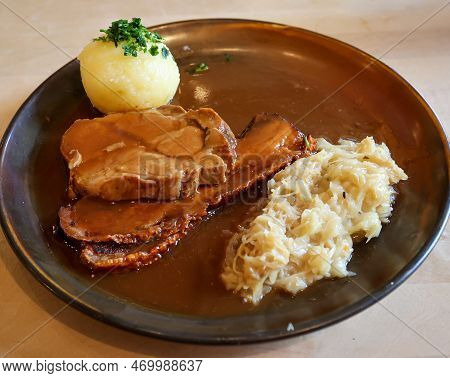A Delicious Roast Pork On A Plate With A Dumpling And Sauerkraut.