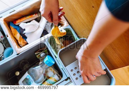 Hand Throws Banana Peel Into Bio-waste Compartment. Separation And Sorting Of Waste At Home, Recycli
