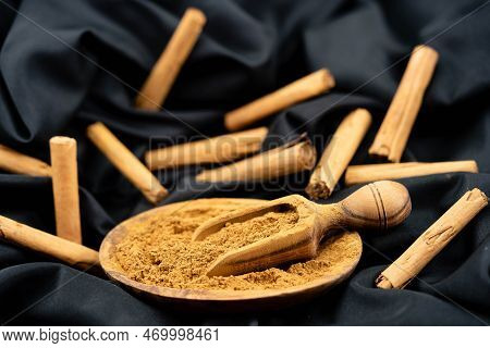 Dried Cinnamon Sticks And Powder On Olive Wood