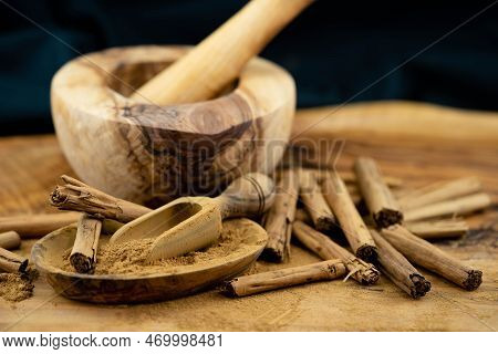 Dried Cinnamon Sticks And Powder On Olive Wood