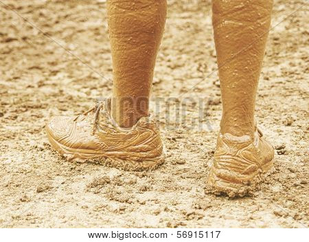 a pair of very muddy shoes and legs