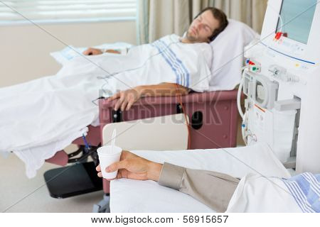 Male patient's hand holding glass of crushed ice in  dialysis unit at hospital