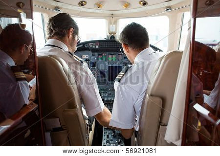 Rear view of pilot and copilot in cockpit of corporate jet