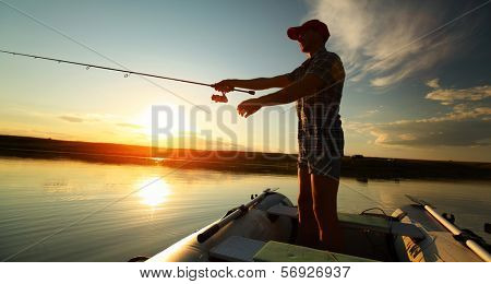 Man fishing from a boat at sunset