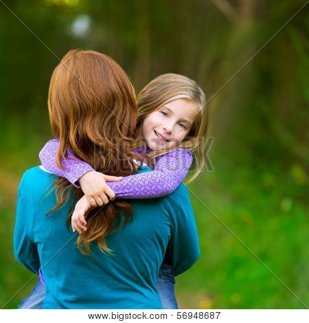 Mum holding daughter kid girl in her arms rear view smiling in outdoor