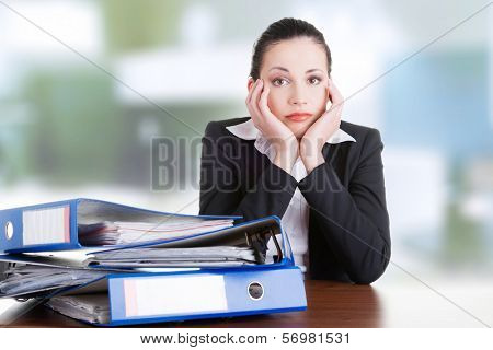 Sad woman with ringbinders sitting at the desk. Tired and exhousted business woman. 