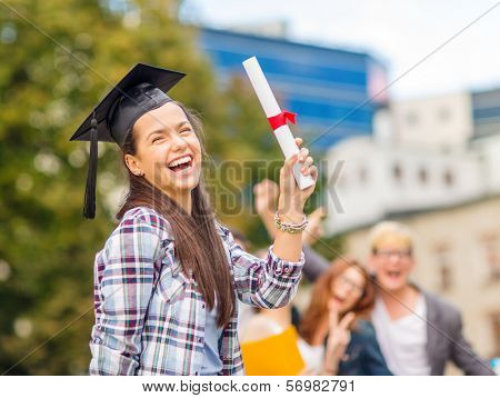 education, campus and teenage concept - smiling teenage girl in corner-cap with diploma and classmates on the back
