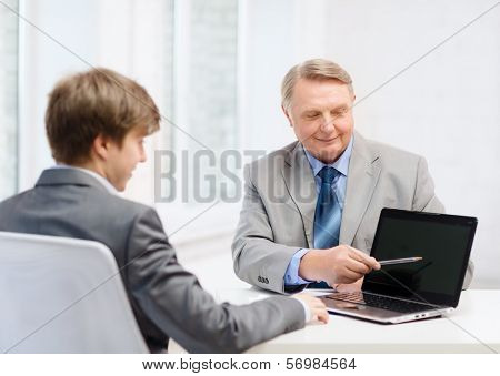 business, advertisement, technology and office concept - older man and young man with laptop computer in office