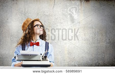Young funny woman in glasses using typewriter