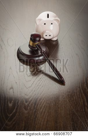 Gavel and Piggy Bank on Reflective Wooden Table.