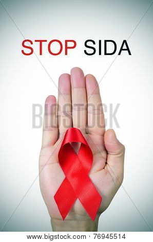 the text stop SIDA, stop AIDS in spanish, french or portuguese, and a red ribbon in a man hand