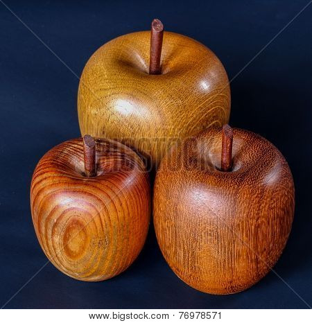 Three Wood Turned Apples On A Deep Blue Background.